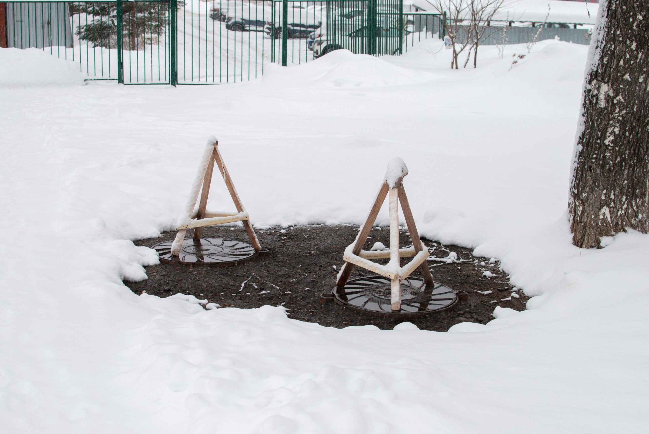 septic tank manhole cover surrounded by snow with a heat hatch above them